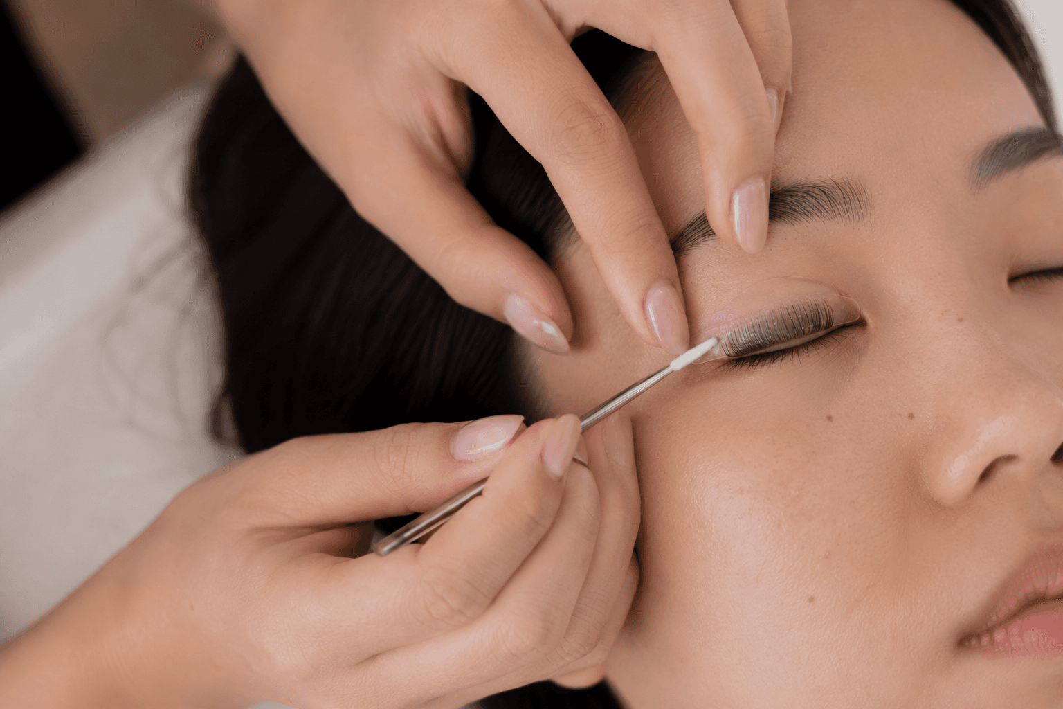 Practitioner hands working carefully on a calm client with eyes closed, warm window light